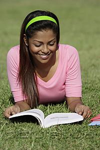 PictureIndia - Young woman laying on grass reading a book