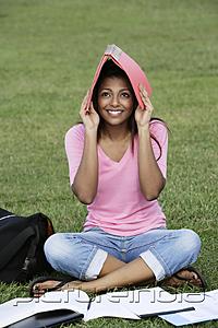 PictureIndia - Young woman covering her head with a folder