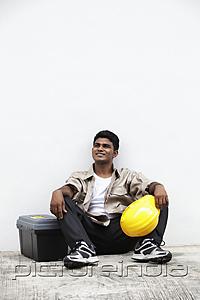 PictureIndia - Man sitting on ground holding construction hat
