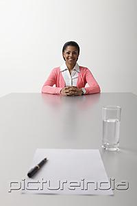 PictureIndia - young woman sitting on end of the table waiting to be interviewed