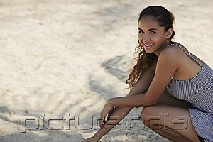 PictureIndia - young woman sitting on sand smiling