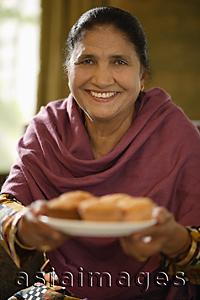 Asia Images Group - older woman offering food, smiling at camera