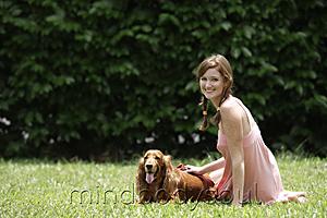 Mind Body Soul - Young woman sitting on grass with her dog