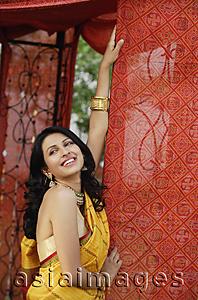 Asia Images Group - smiling young woman in sari, red tent