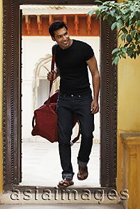Asia Images Group - man coming through doorway with duffel bag
