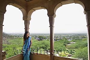 Asia Images Group - young woman in sari leaning against pillar on terrace balcony