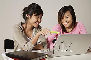 AsiaPix - Two women sitting at desk and using a laptop.
