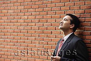 Asia Images Group - businessman leaning against wall