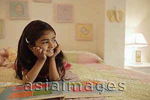 Asia Images Group - little girl reading book on bed