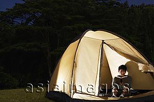 Asia Images Group - Man reading inside tent