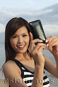 Asia Images Group - Young woman taking photo with camera phone