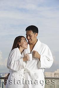 Asia Images Group - Young couple in robes smiling at each other