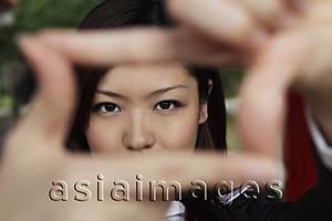Asia Images Group - Young woman looking through fingers making a frame