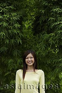 Asia Images Group - Young woman smiling in front of bamboo trees