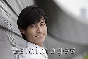 Asia Images Group - Head shot of man smiling in front of wall