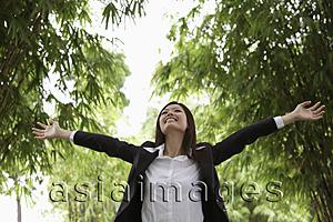Asia Images Group - Young woman wearing a suit and raising her arms up outside