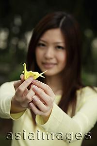 Asia Images Group - Young woman holding yellow crane