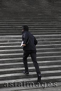 Asia Images Group - Man running up stairs wearing a suit