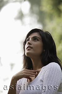 Asia Images Group - Back lit head shot of young woman looking up to the sky hand on neck