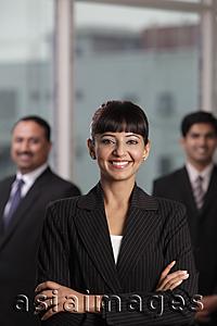 Asia Images Group - Indian woman smiling with arms folded in front of two colleagues