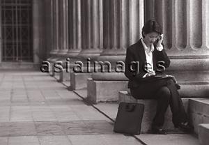 Asia Images Group - Female executive sitting, using cellular phone
