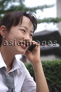 Asia Images Group - Female executive talking on cellular phone, smiling
