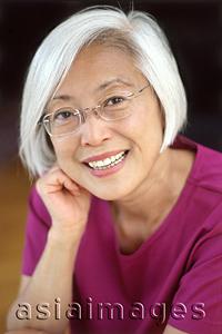 Asia Images Group - Mature woman with glasses resting head on fist, portrait