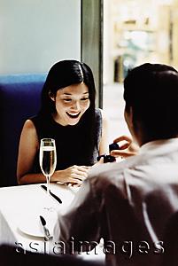 Asia Images Group - Man presenting engagement ring to woman in restaurant