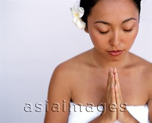 Asia Images Group - Woman with flower in hair, palms raised, white background