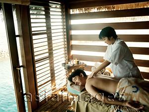 Asia Images Group - Man receiving massage from woman, water in background.