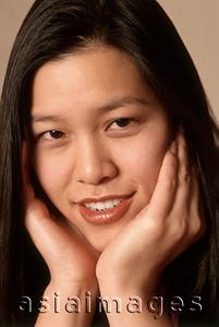 Asia Images Group - Young woman with hands on chin, smiling, portrait