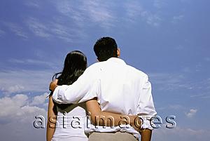 Asia Images Group - Young couple embracing with blue sky in background, rear view