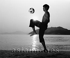 Asia Images Group - Man playing with football (soccer ball) on beach, silhouette