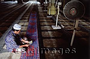 Asia Images Group - Singapore, A Muslim man reading in the quiet of a Mosque along Arab Street.