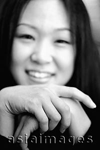 Asia Images Group - Young woman with hands clasped, smiling.