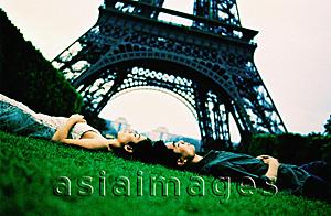 Asia Images Group - Young couple lying on grass, Eiffel Tower in background. (high-grained)