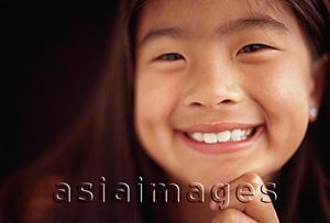Asia Images Group - Young girl smiling with hand on chin, toothy smile