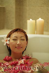 Asia Images Group - Woman relaxing in tub, flowers floating around her
