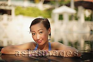 Asia Images Group - Young woman at the edge of a pool, looking at camera