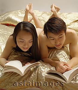 Asia Images Group - Couple reading on bed.