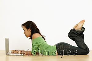 Asia Images Group - Young woman using laptop, lying on floor