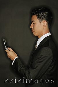 Asia Images Group - Young man using mobile phone, text messaging