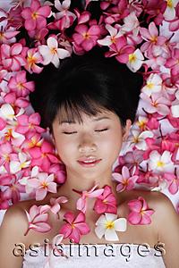 Asia Images Group - Young woman lying down amidst flowers, eyes closed