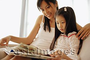 Asia Images Group - Mother and daughter, sitting side by side, looking at book