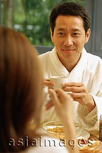 Asia Images Group - Couple facing each other, holding cups of coffee