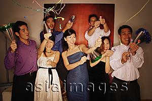 Asia Images Group - Group of friends having a party at home, playing with streamers and noisemakers