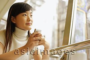 Asia Images Group - Young woman holding mobile phone, looking away