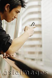 Asia Images Group - Young man using mobile phone, sideview