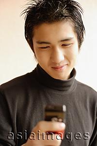 Asia Images Group - Young man using mobile phone, smiling