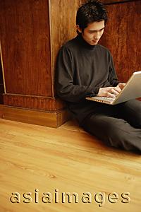 Asia Images Group - Young man using laptop, sitting on floor
